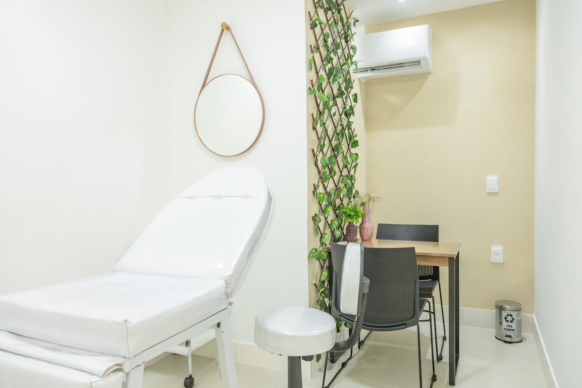 Sala 1 do coworking da AV Clínica Integrada — maca de atendimento, espelho e mesa de apoio